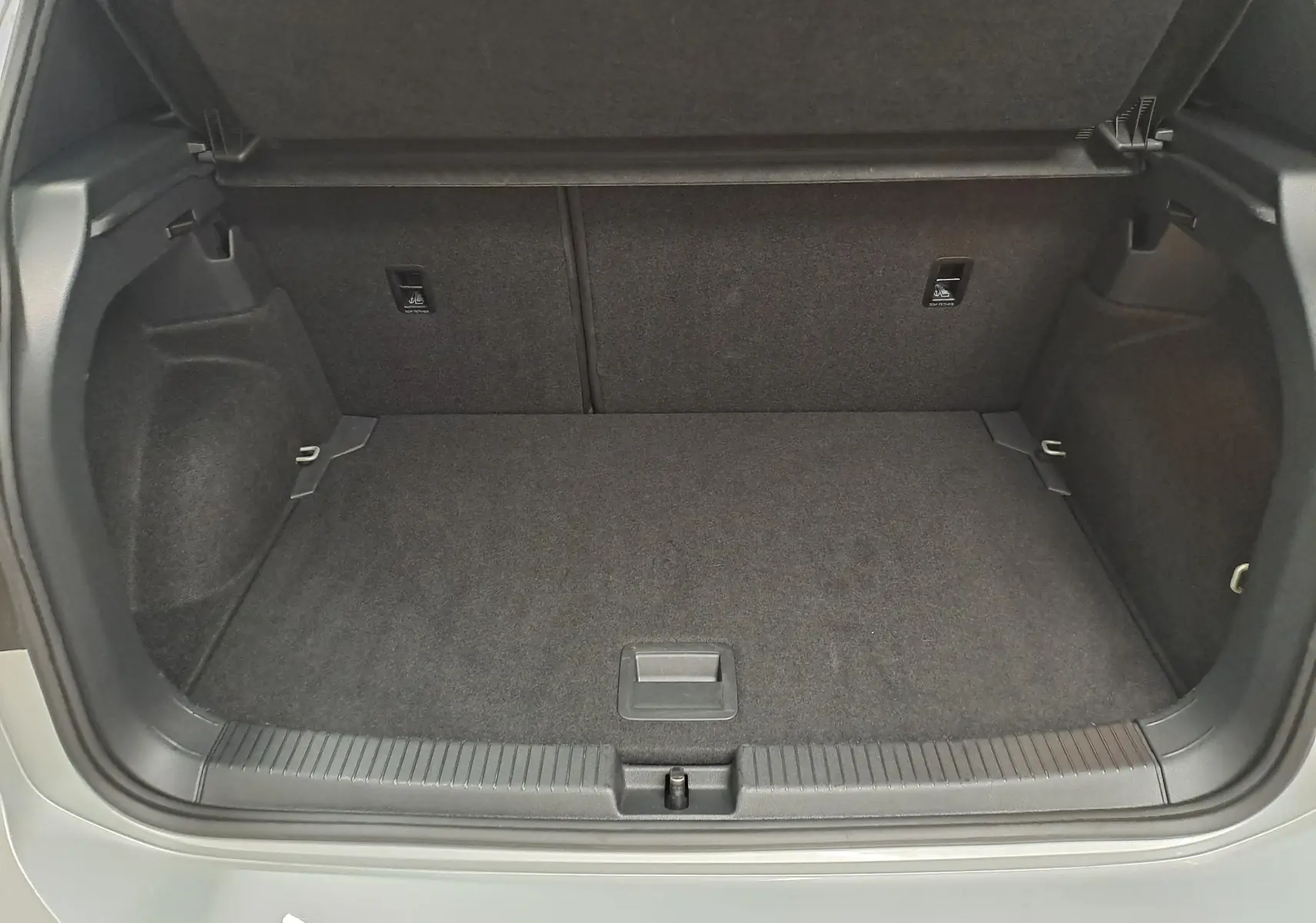 Coffre ouvert vu de l'arrière d'un Volkswagen T-Cross 2025 gris Reflet d'argent, espace de chargement vide et propre.