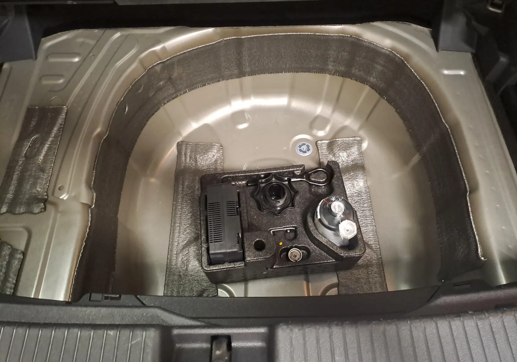 Vue rapprochée de la roue de secours et du kit de réparation dans le coffre du Volkswagen T-Cross 2025 couleur Reflet d'Argent.