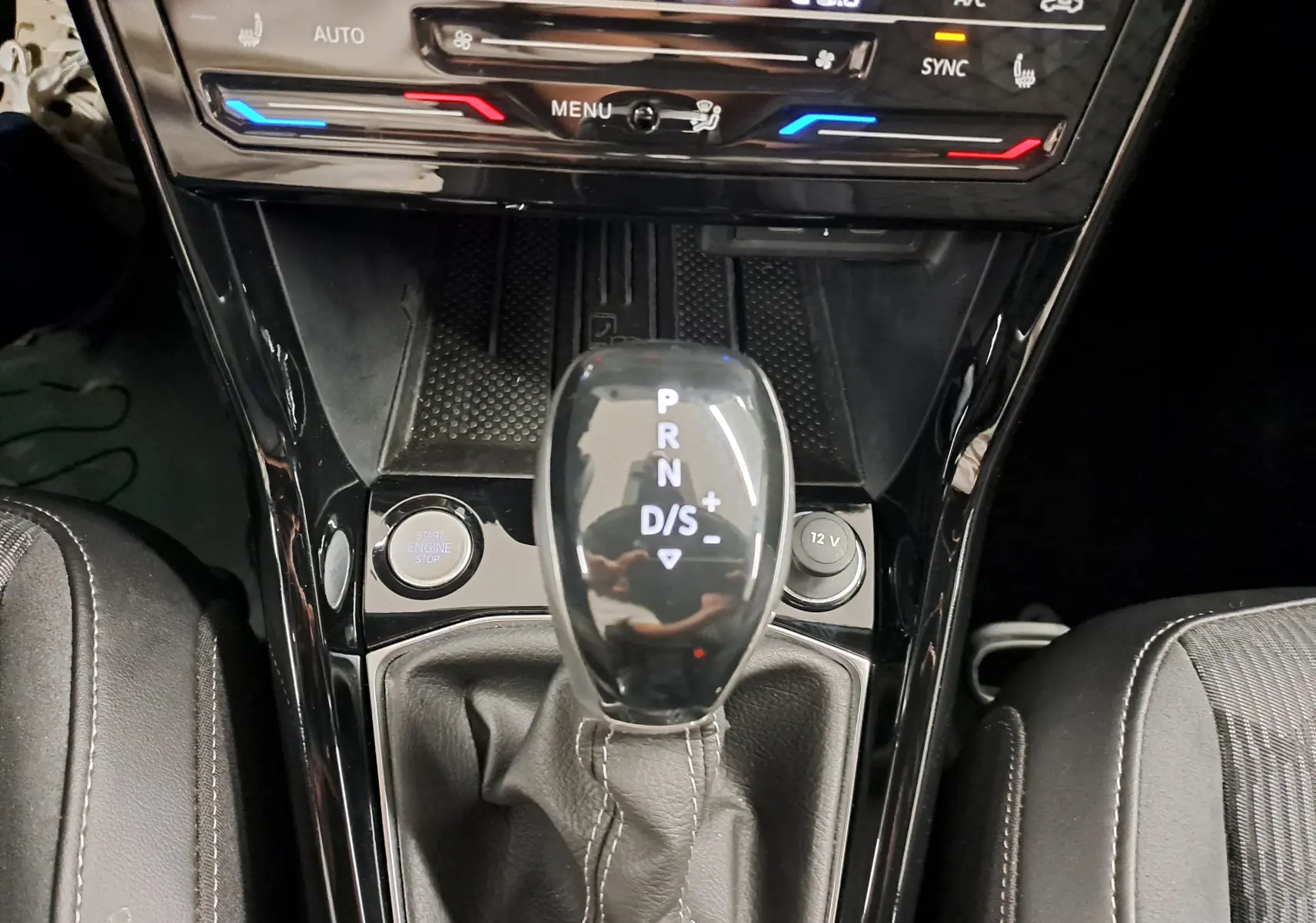 Le levier de vitesses automatique DSG7 du Volkswagen T-Cross 2025, entouré de la console noire brillante avec bouton start et prise 12V.