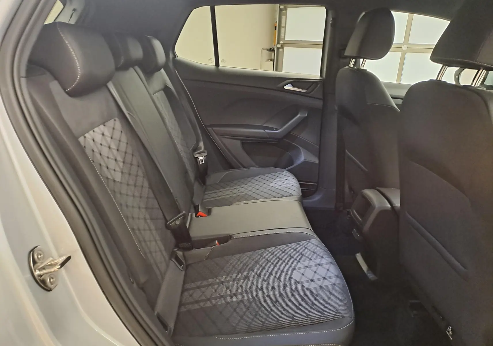Vue intérieure côté gauche des sièges arrière du Volkswagen T-Cross 2025 en Reflet d'Argent avec sellerie noire à motifs géométriques.