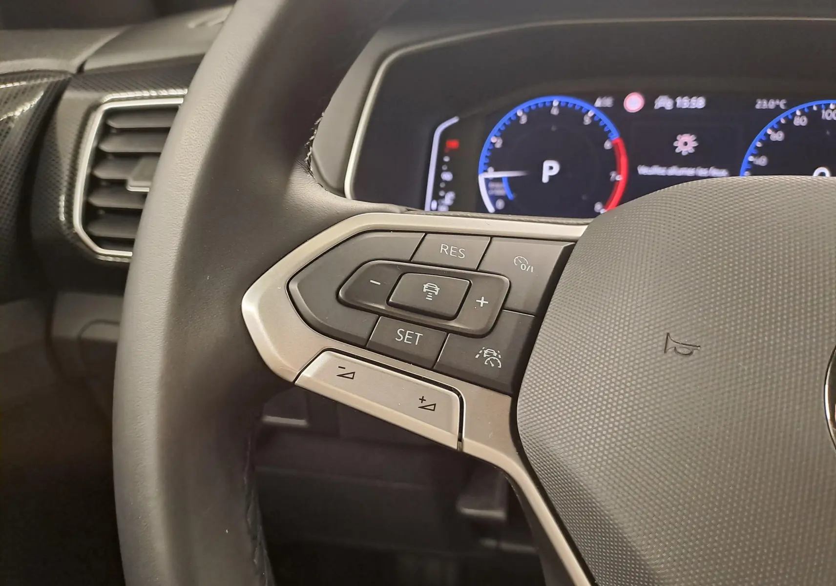 Gros plan sur le volant multifonction du Volkswagen T-Cross 2025 avec commandes de régulateur et tableau de bord numérique.