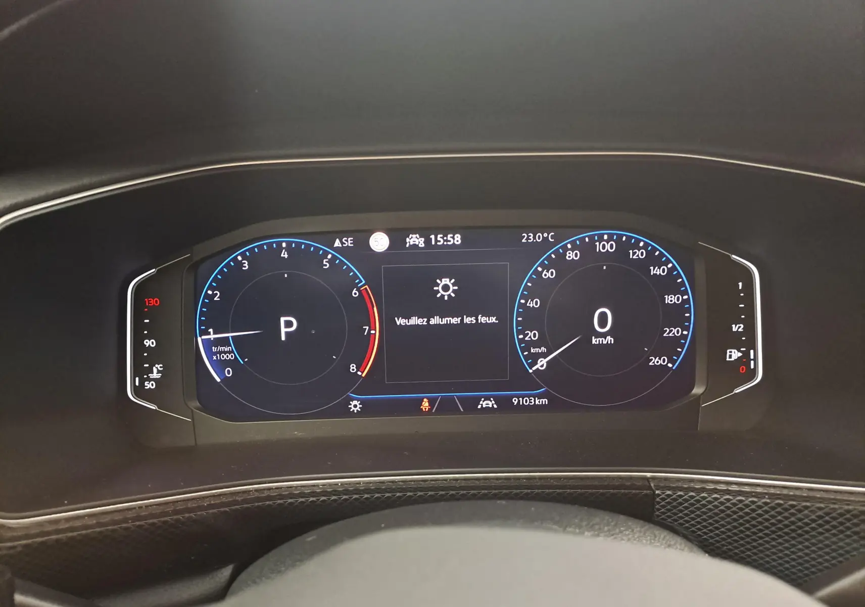 Tableau de bord numérique du Volkswagen T-Cross 2025 affichant la vitesse à 0 km/h et l'indication d'allumer les feux.