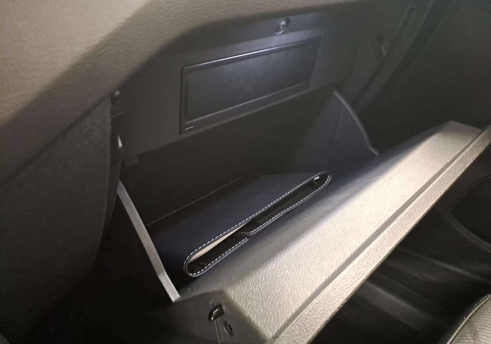 Gant de poche noir dans la boîte à gants ouverte du Volkswagen T-Cross 2025 couleur Reflet d'Argent.