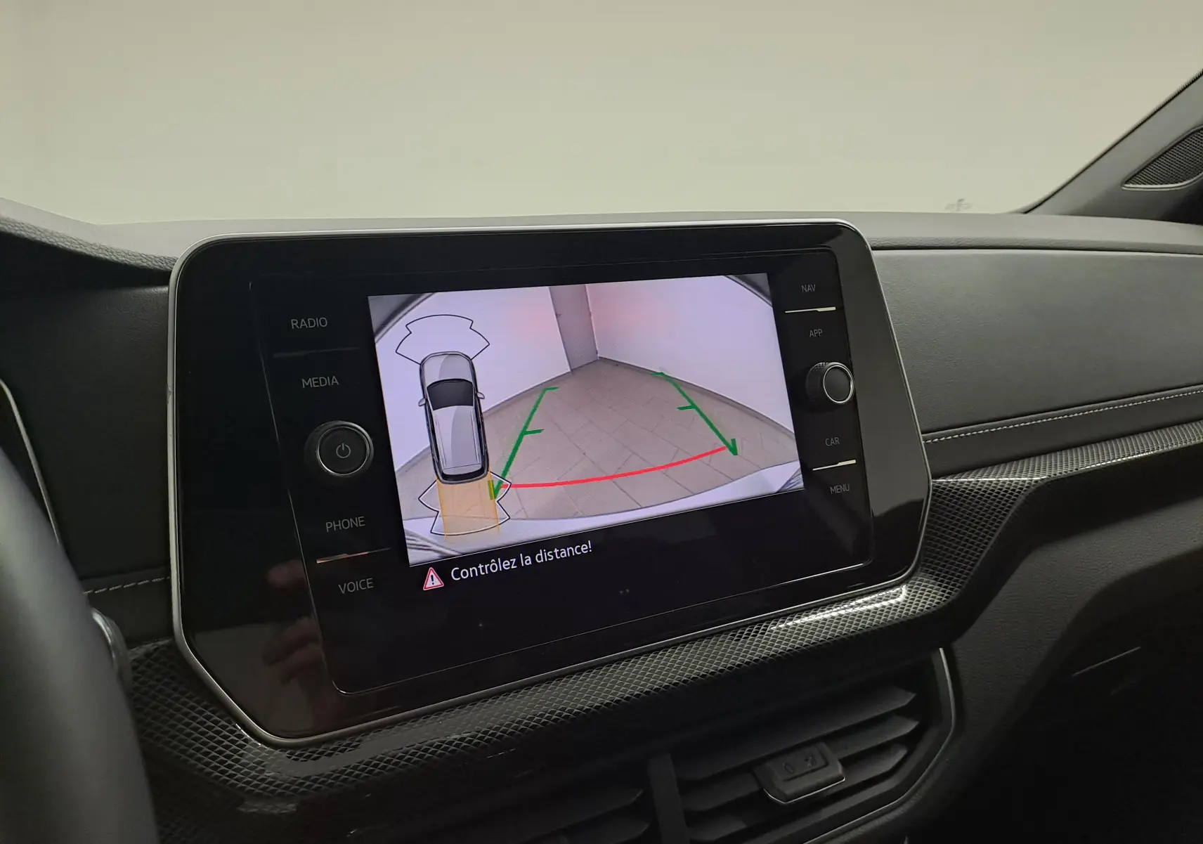 Écran central du Volkswagen T-Cross 2025 affichant la caméra de recul avec guidage de trajectoire en intérieur.