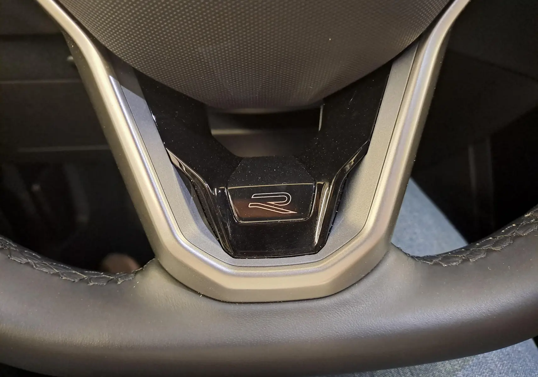 Gros plan sur le volant cuir du Volkswagen T-Cross 2025 R-Line avec logo R au centre, intérieur noir.