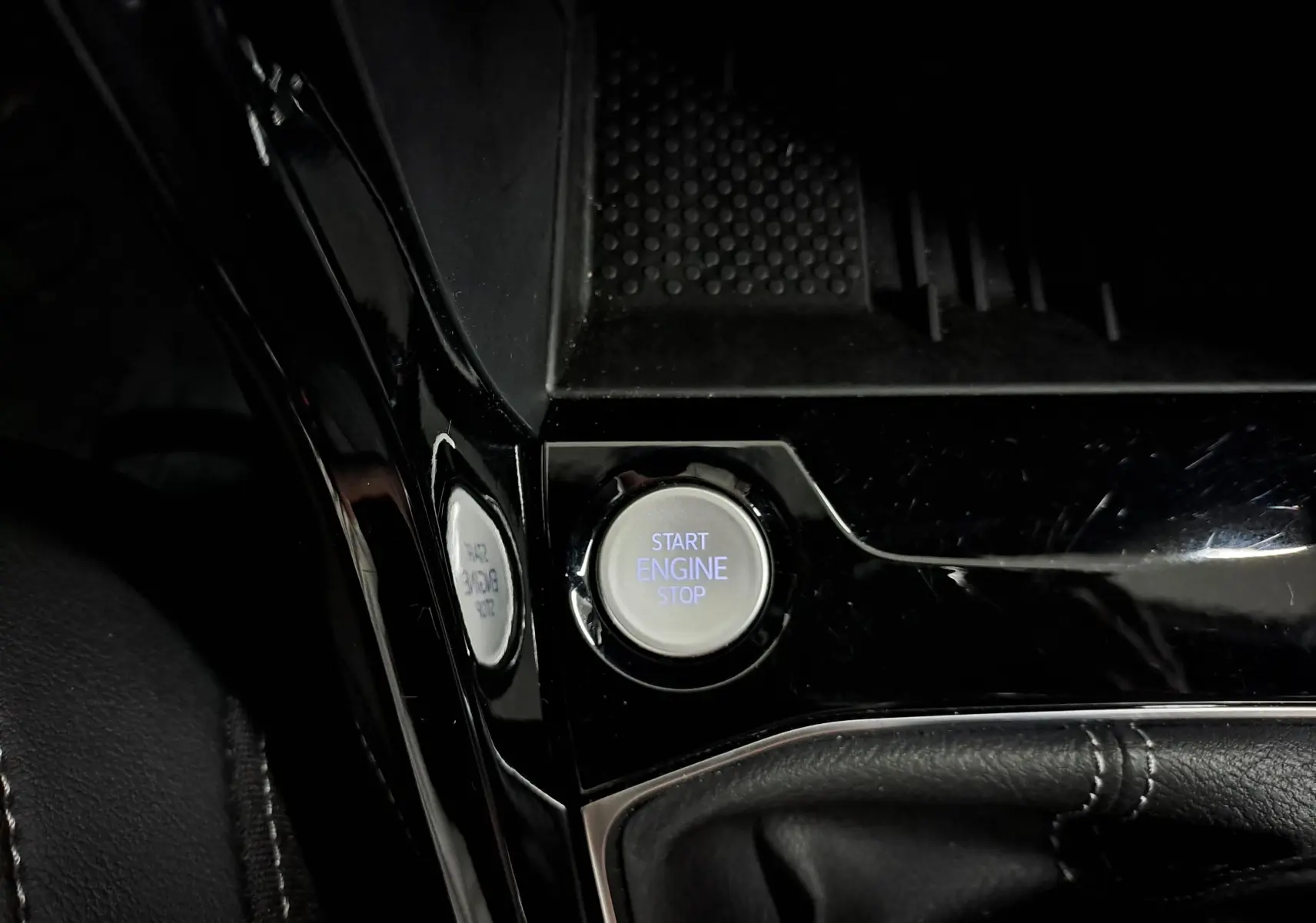 Bouton start engine stop en gros plan sur la console centrale noire brillante du Volkswagen T-Cross 2025 finition R-Line Edition