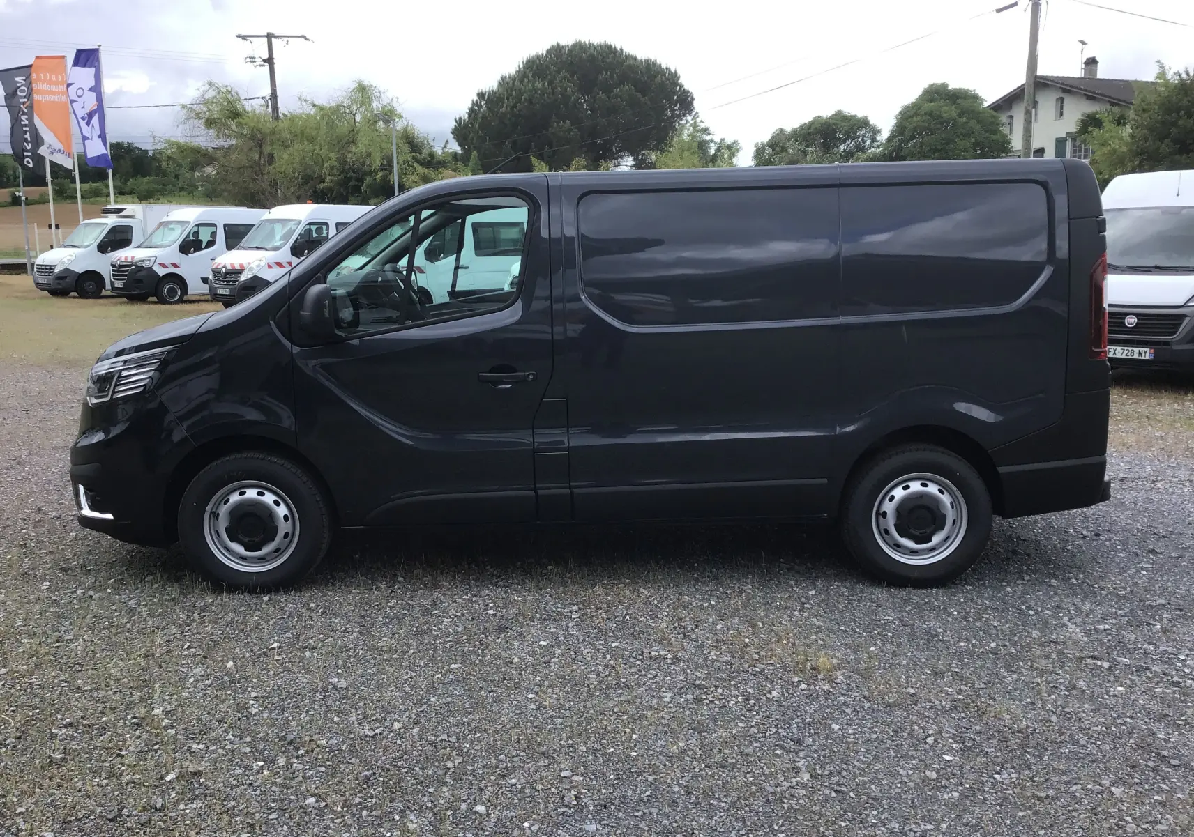 Vue de profil côté gauche d’un Renault Trafic Fourgon gris comète 2025, avec carrosserie lisse et jantes acier.