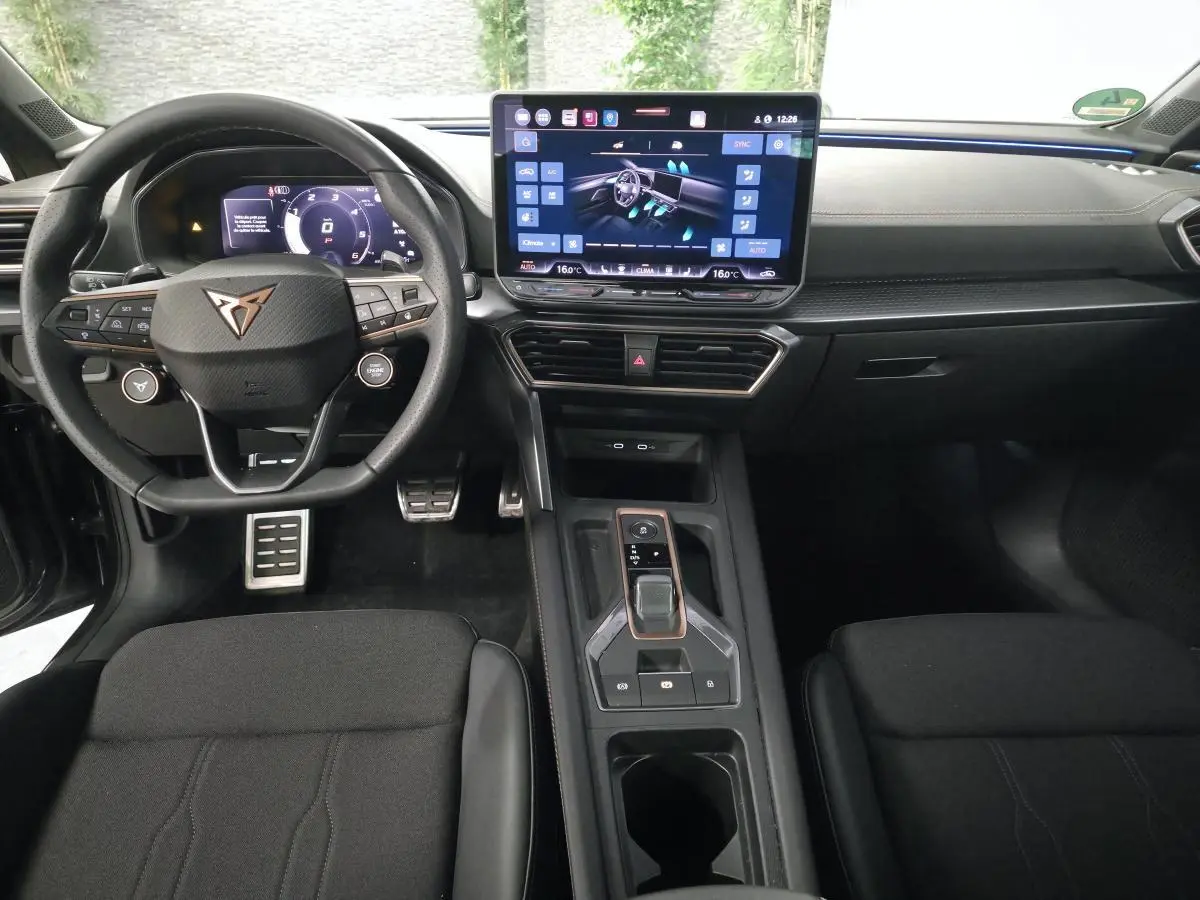Vue intérieure avant de la CUPRA Leon 2025 gris, volant Supersports, écran tactile HD et console centrale moderne.