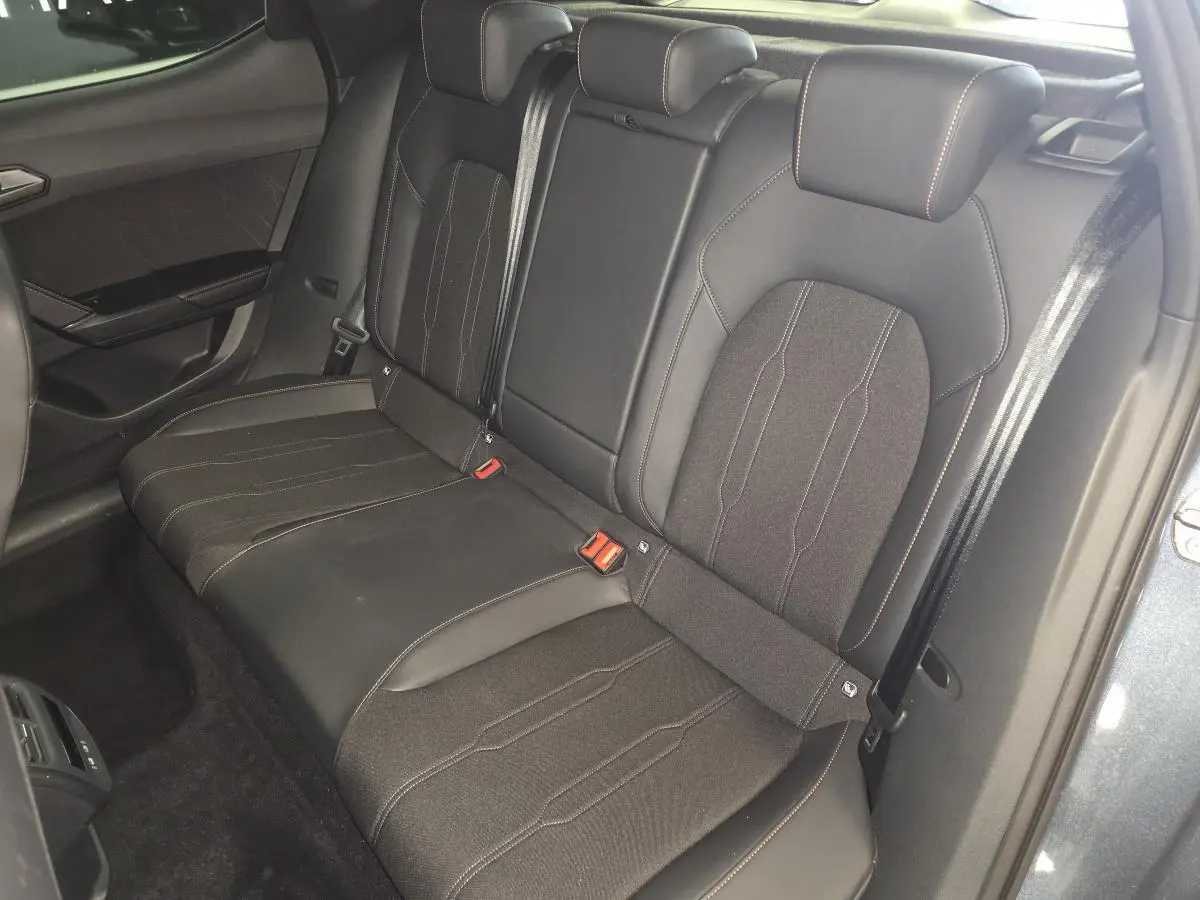 Vue intérieure arrière montrant la banquette bimatière noire du CUPRA Leon 2025 avec surpiqûres cuivrées.