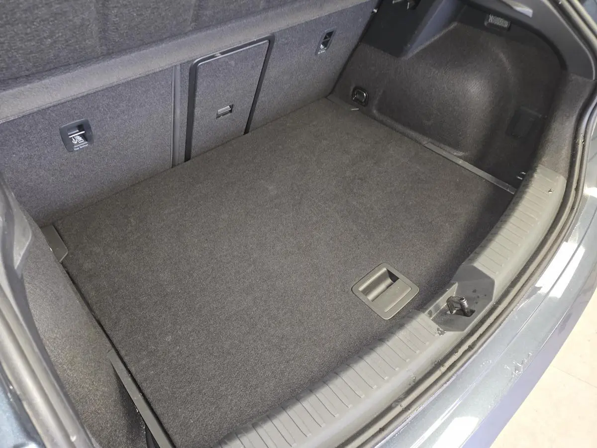 Vue plongeante sur le coffre spacieux et propre d'une CUPRA Leon gris, avec revêtement intérieur sombre et finitions nettes.
