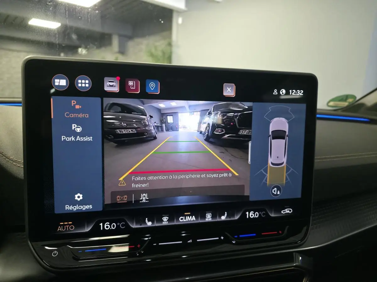 Écran tactile intérieur affichant l'aide au stationnement avec vue caméra arrière dans une CUPRA Leon gris.