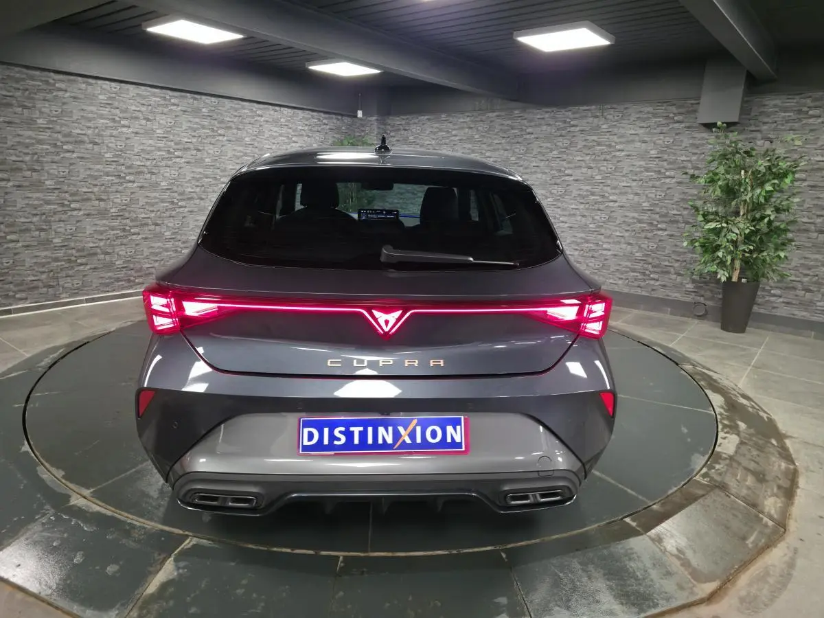 Vue arrière d'une CUPRA Leon gris magnétique avec feux arrière en bandeau lumineux Tri-LED et double sortie d'échappement noire.