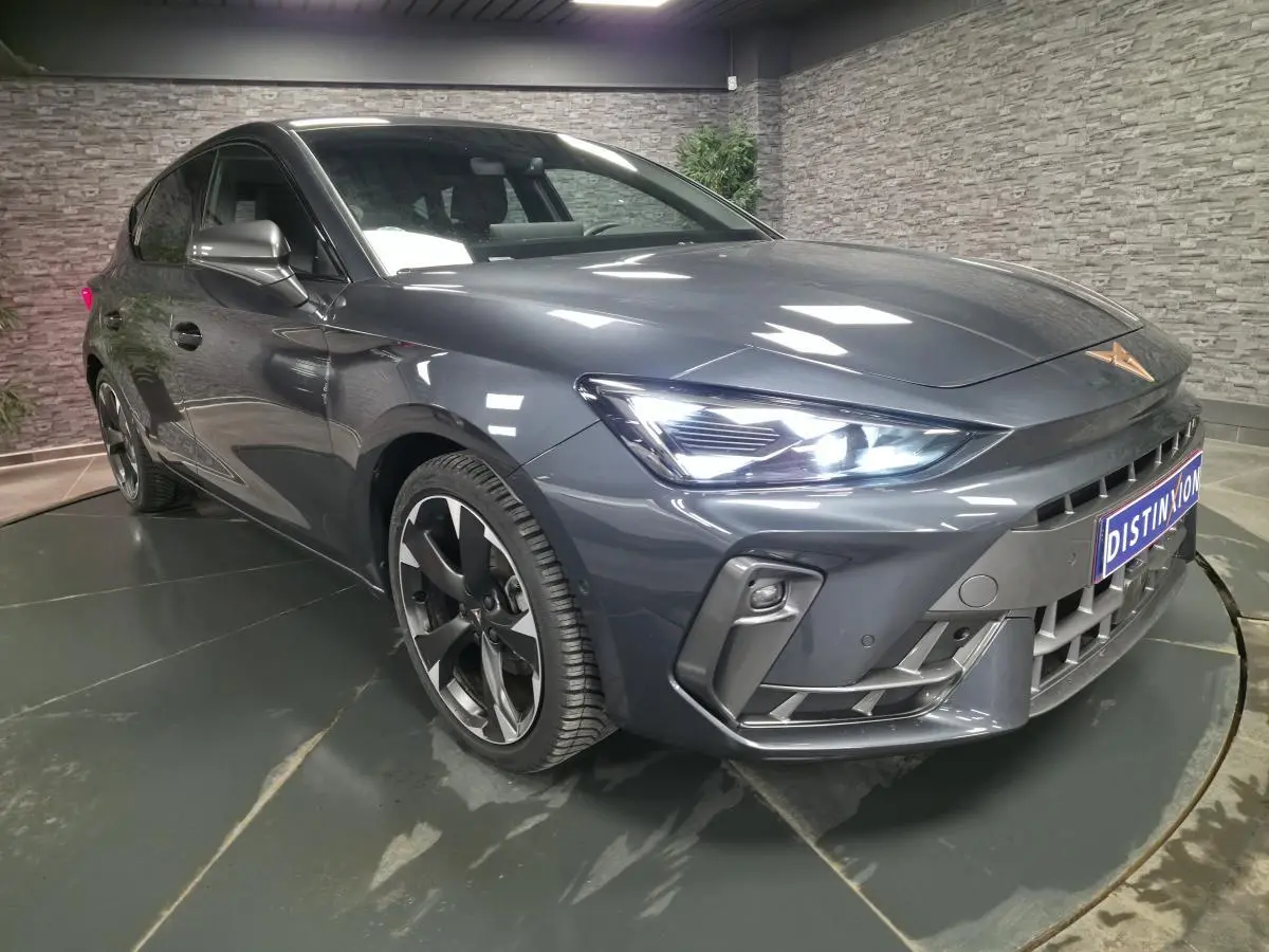 Vue 3/4 avant d'une CUPRA Leon gris magnétique avec phares Tri-LED allumés et jantes alliage 18 pouces.