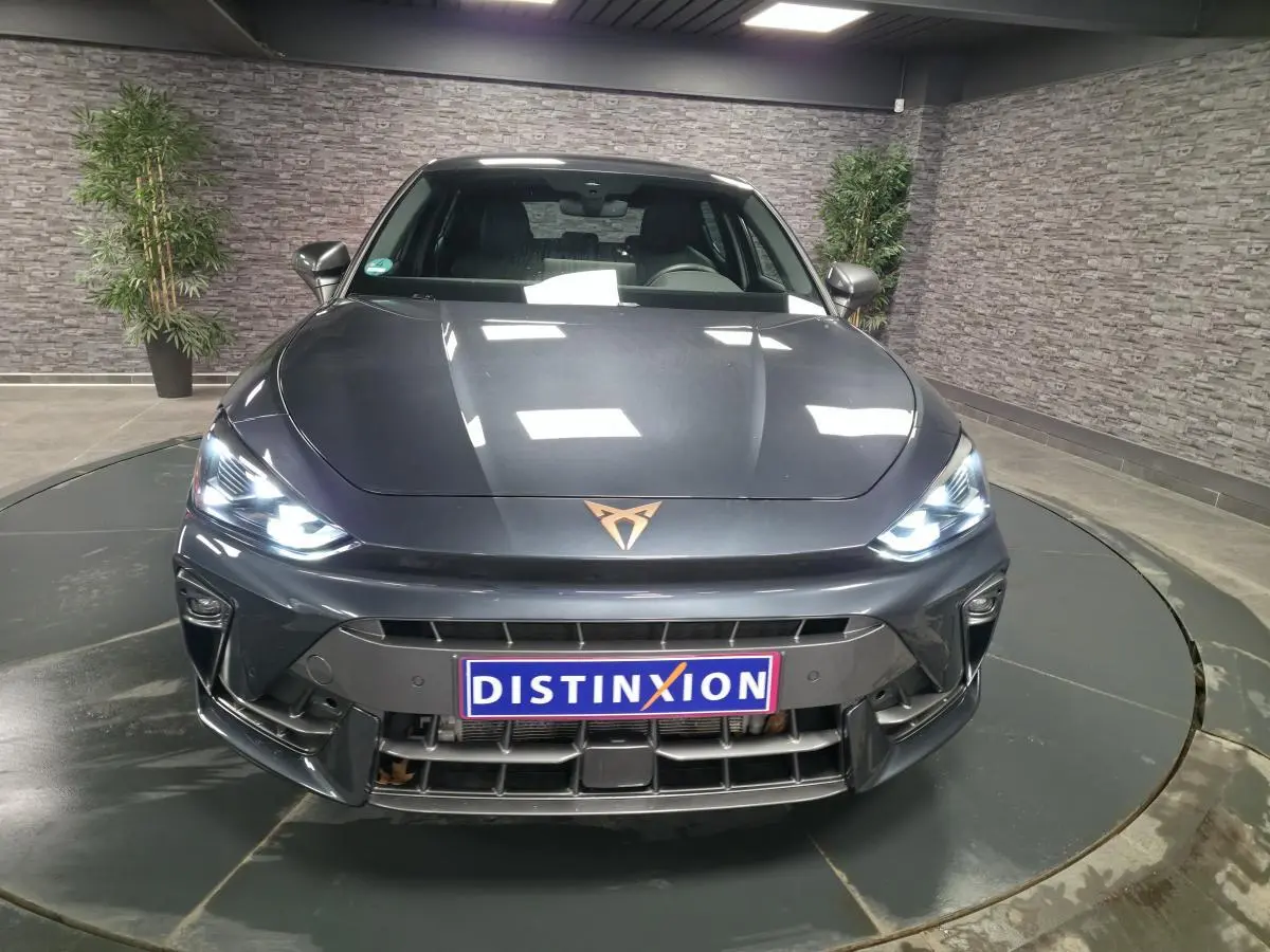 Vue avant d'une CUPRA Leon gris magnétique avec phares Tri-LED allumés et logo CUPRA cuivré sur le capot.