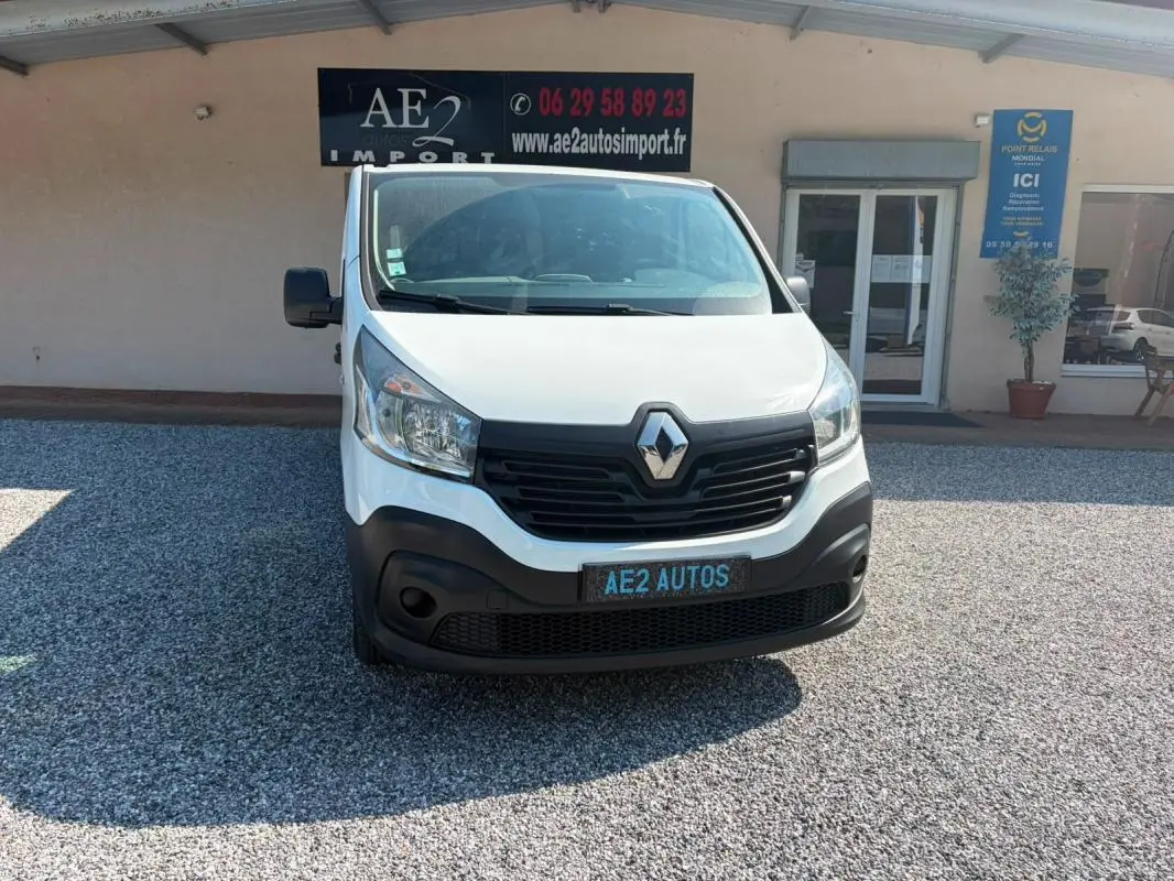 Vue de face d’un Renault Trafic Fourgon blanc de 2018, avec calandre noire et plaque AE2 AUTOS visible.