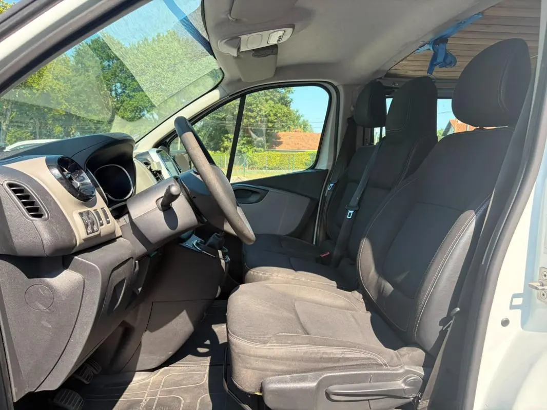 Vue intérieure côté conducteur du Renault Trafic Fourgon blanc 2018, montrant les sièges et le tableau de bord.