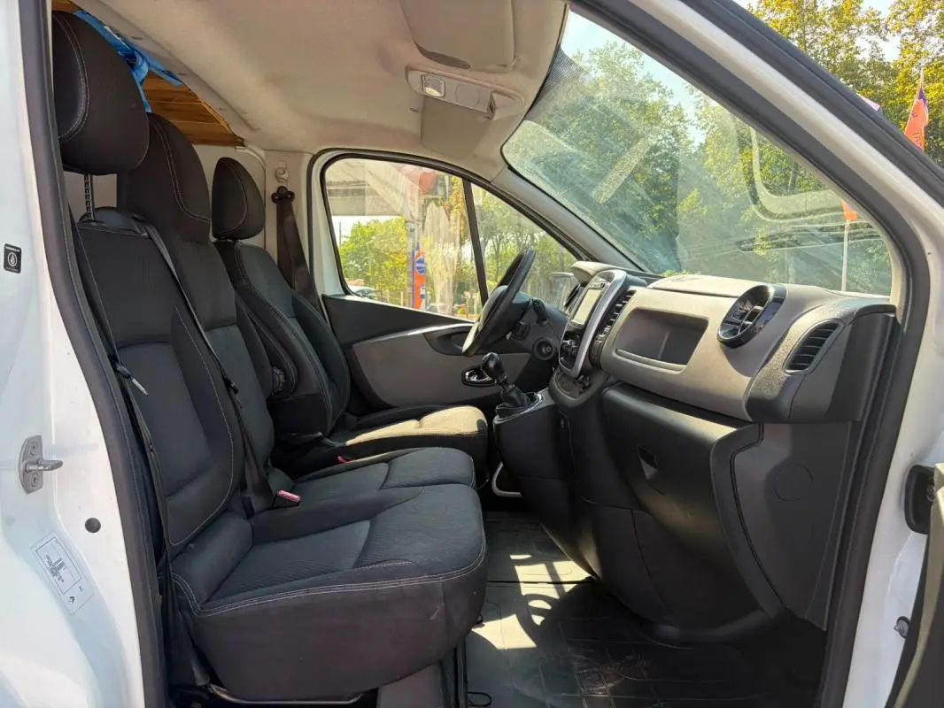 Vue intérieure côté conducteur du Renault Trafic Fourgon blanc 2018, montrant les sièges noirs et le tableau de bord.