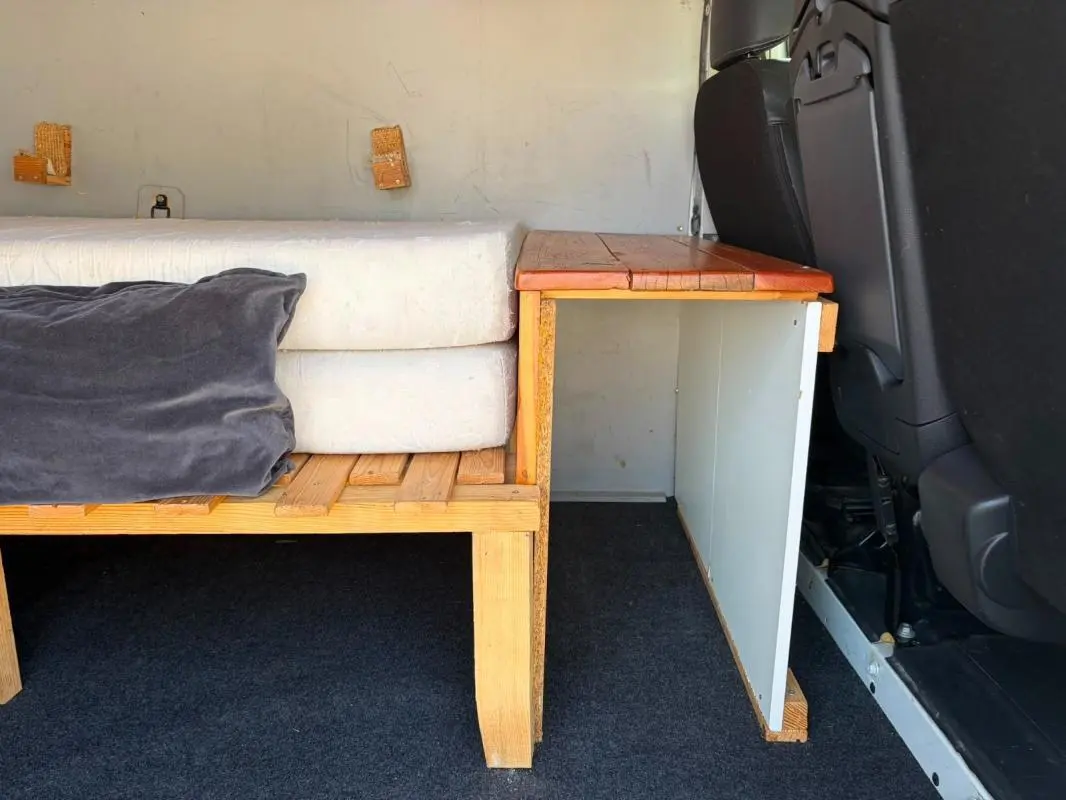 Vue intérieure latérale droite du Renault Trafic Fourgon blanc de 2018, montrant un aménagement en bois avec coussins.