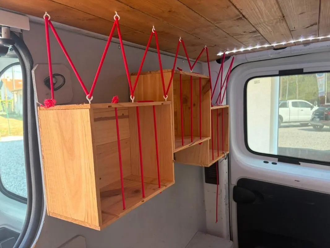 Intérieur du Renault Trafic Fourgon blanc 2018, vue latérale gauche montrant des étagères en bois suspendues par des cordes rouges.