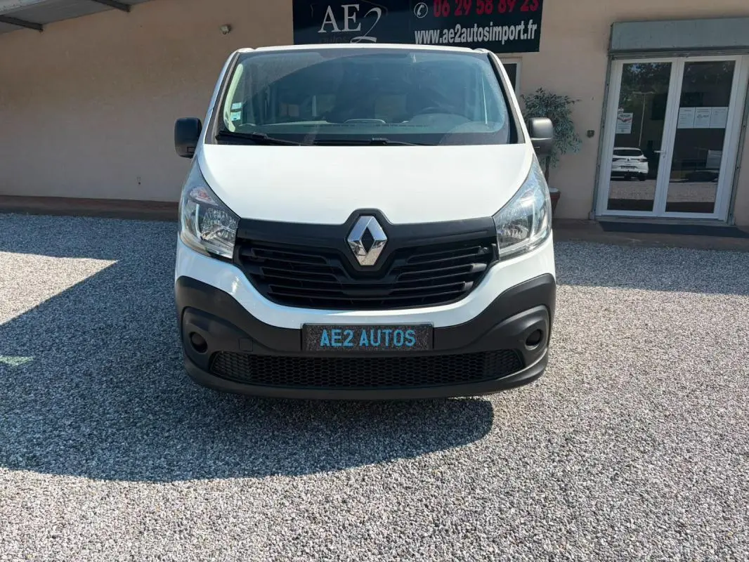 Vue frontale d’un fourgon Renault Trafic blanc de 2018 avec calandre noire et plaque AE2 AUTOS.