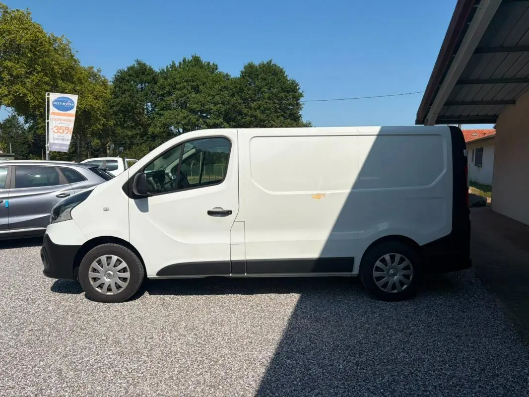Vue de profil côté gauche du Renault Trafic Fourgon blanc 2018, avec une tache visible sur la porte latérale.