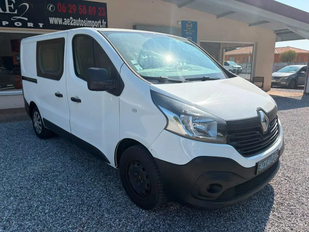 Renault Trafic Fourgon blanc vu en 3/4 avant droit, avec pare-chocs noir et vitres latérales teintées.
