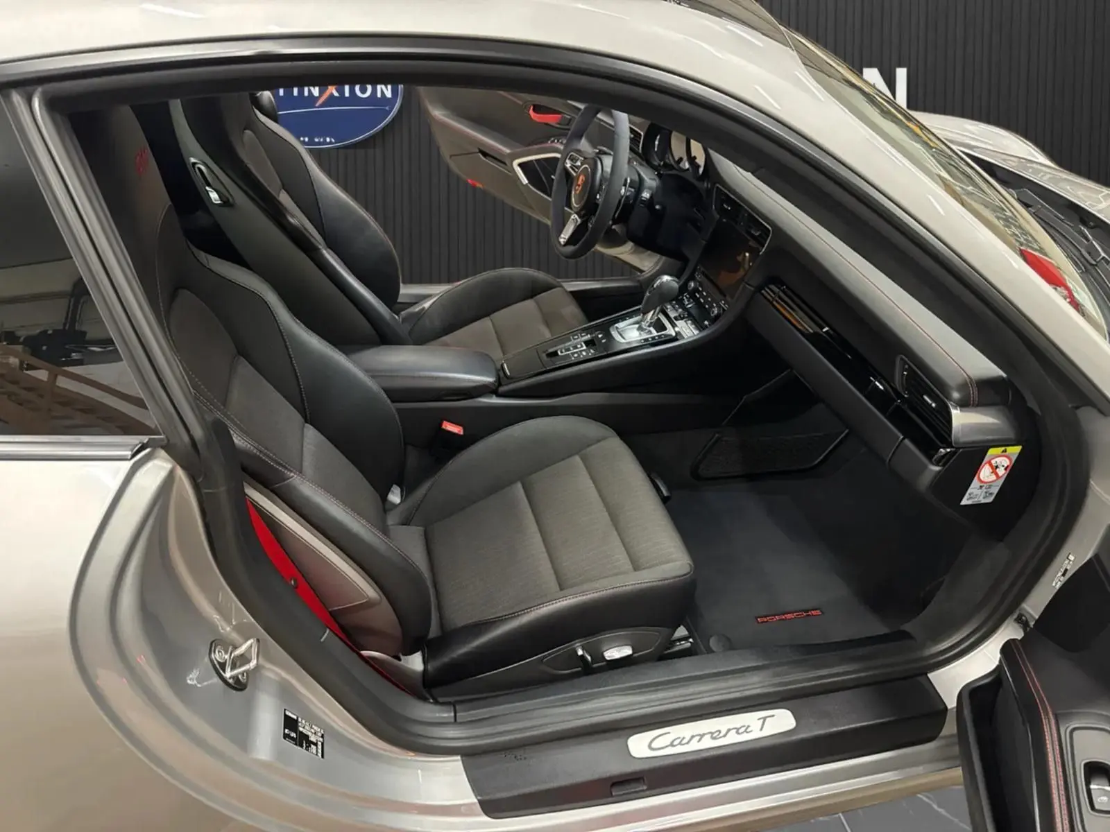 Vue intérieure côté conducteur de la Porsche 911 991 2 Carrera T gris GT Silver avec sièges sport noirs et volant alcantara.