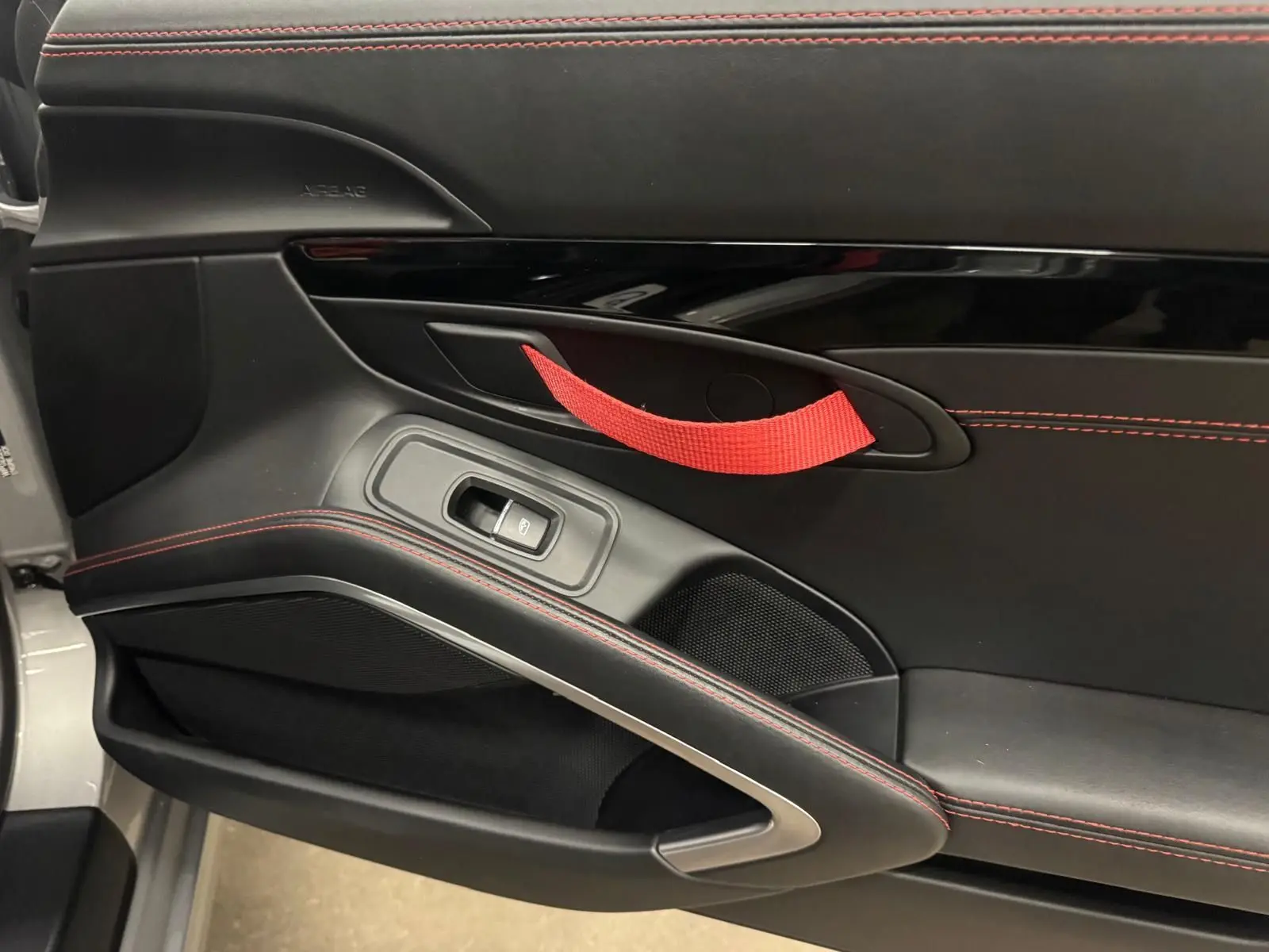 Gros plan sur la porte intérieure gauche noire avec surpiqûres rouges et poignée de maintien rouge du Porsche 911 991.2 Carrera T.