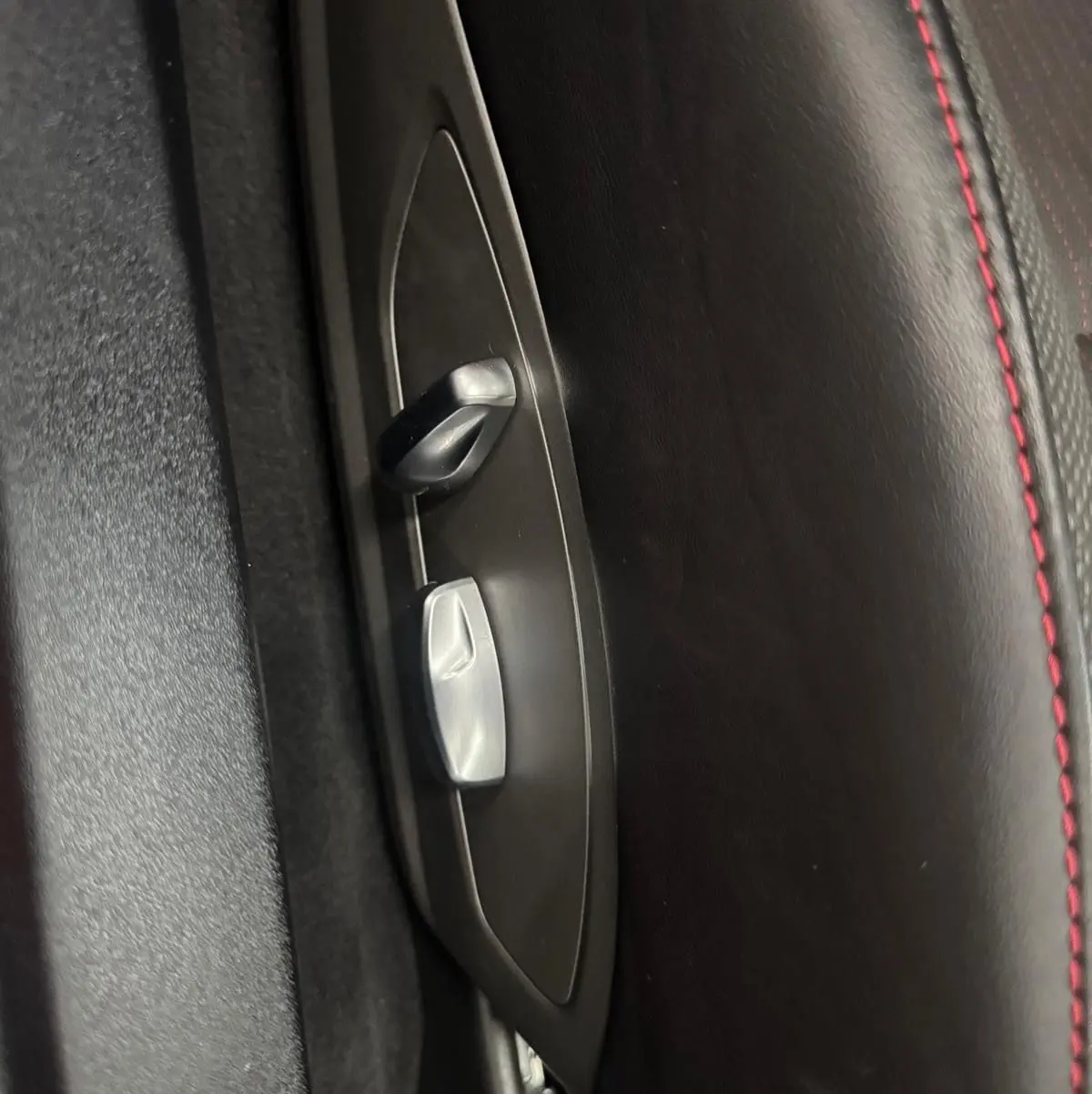 Gros plan sur les commandes de réglage électrique du siège en cuir noir avec surpiqûres rouges d'une Porsche 911 991 2 Carrera T.