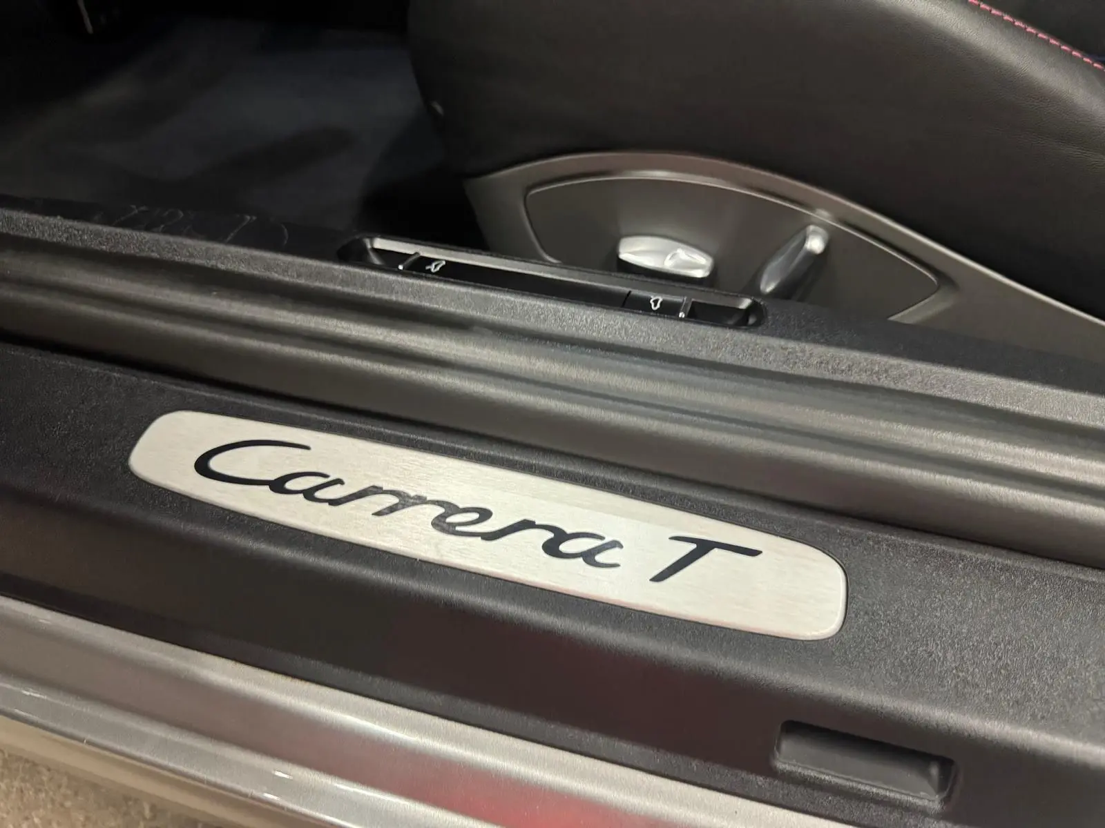 Gros plan sur la plaque de seuil de porte "Carrera T" à l'intérieur d'une Porsche 911 gris GT Silver.