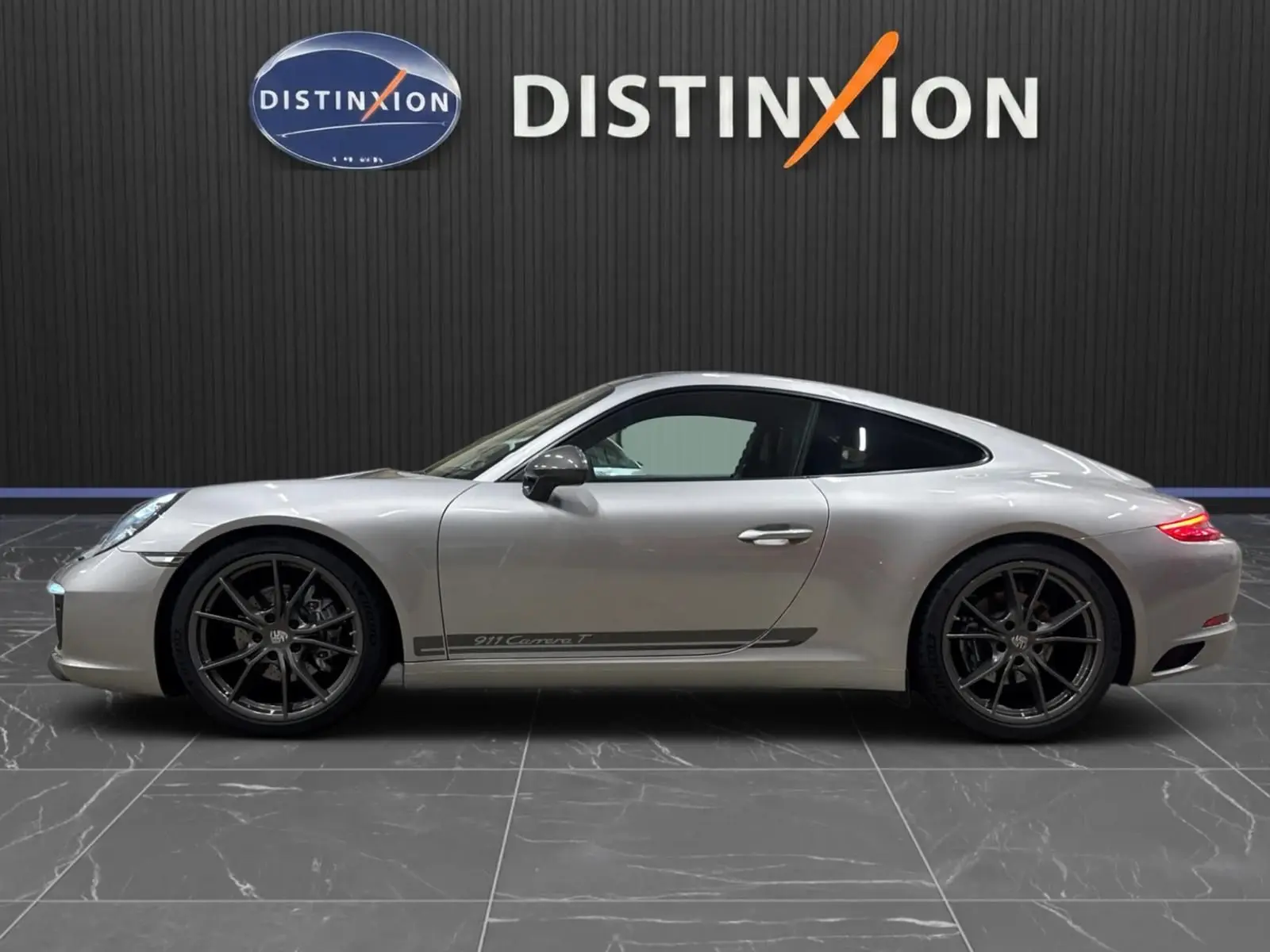 Profil droit d'une Porsche 911 991.2 Carrera T gris GT Silver avec jantes Carrera S noires et logo latéral distinctif.