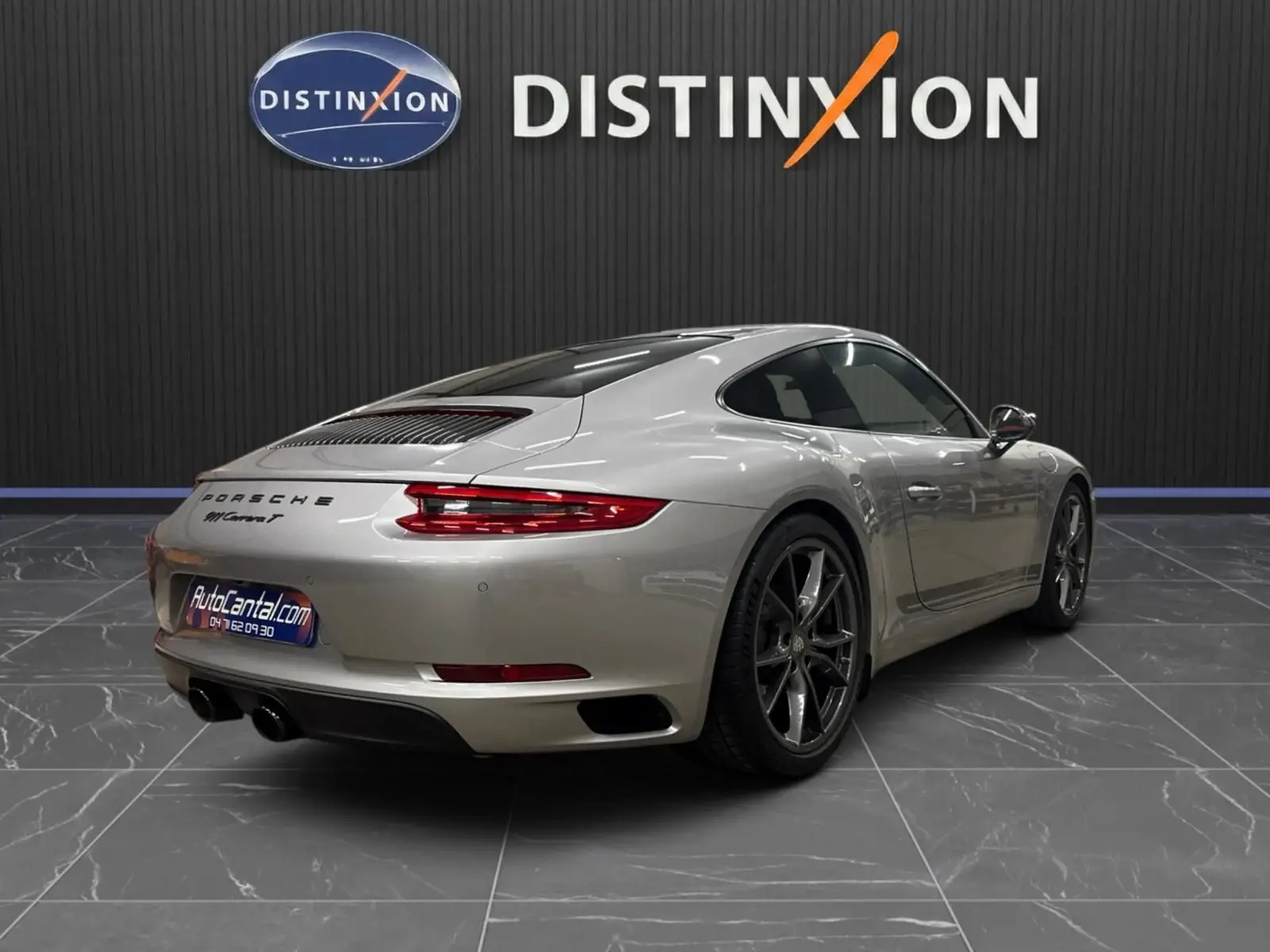 Vue 3/4 arrière droite d'une Porsche 911 Carrera T 991 gris GT Silver avec jantes Carrera S 20 pouces dans un showroom.