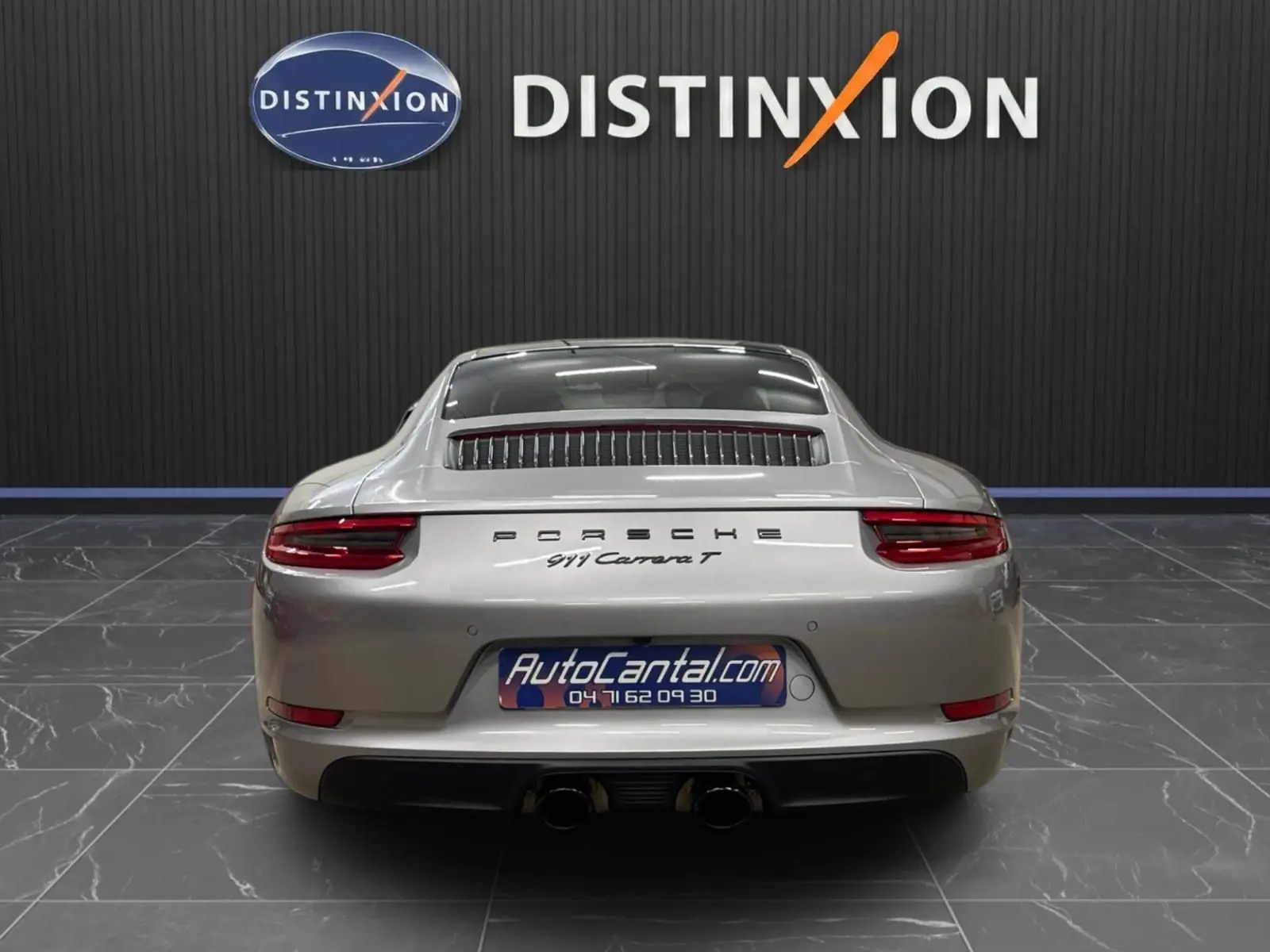 Vue arrière d'une Porsche 911 Carrera T 2018 gris GT Silver avec double sortie d'échappement et logo Porsche visible.