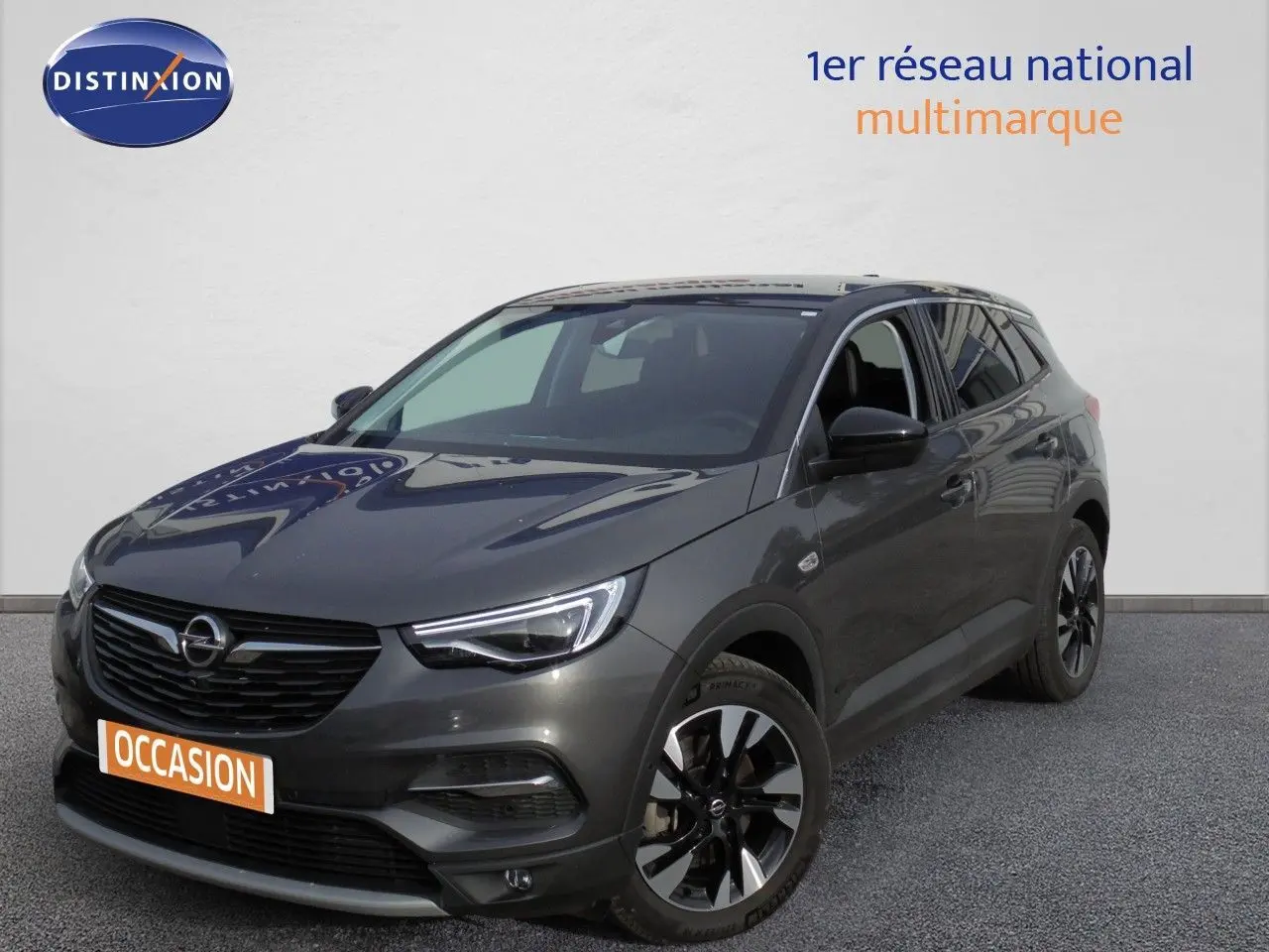 Opel Grandland X gris Moai métal en 3/4 avant droit, avec jantes alliage et calandre noire distinctive.
