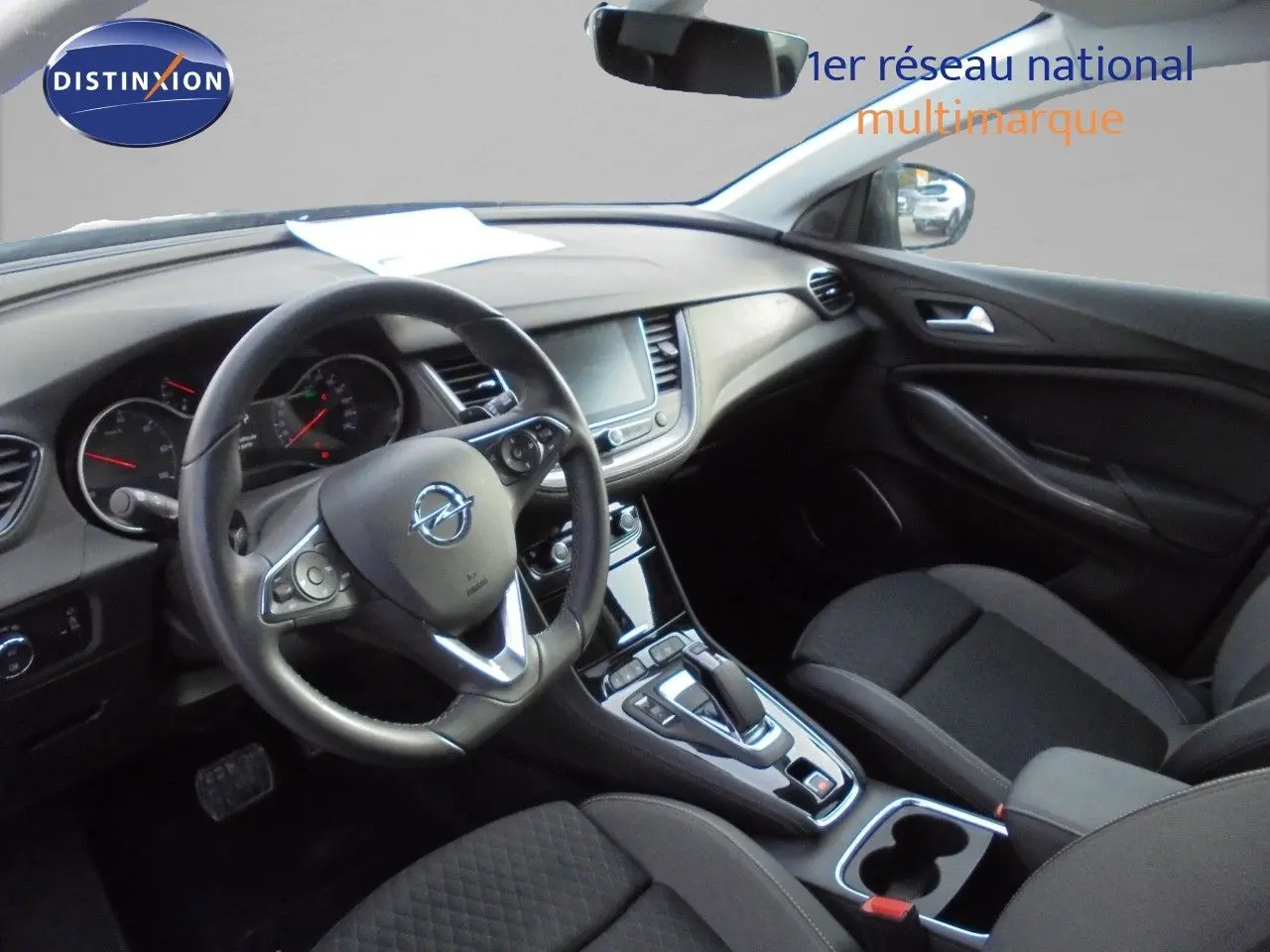Vue intérieure côté conducteur de l’Opel Grandland X gris Moai, montrant le volant, tableau de bord et console centrale.