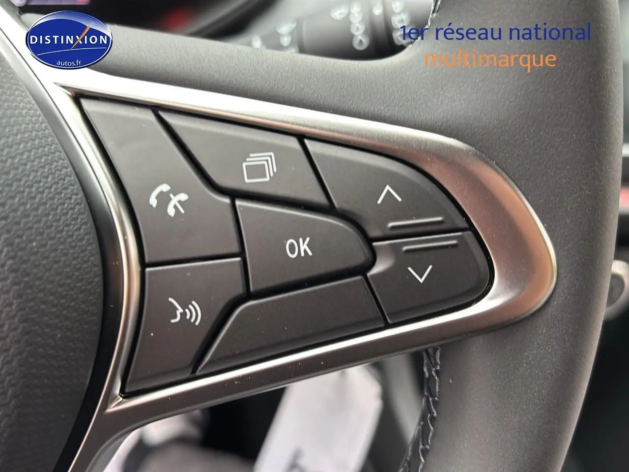 Gros plan sur les commandes multifonctions noires du volant d'une Renault Clio V noire, côté gauche.