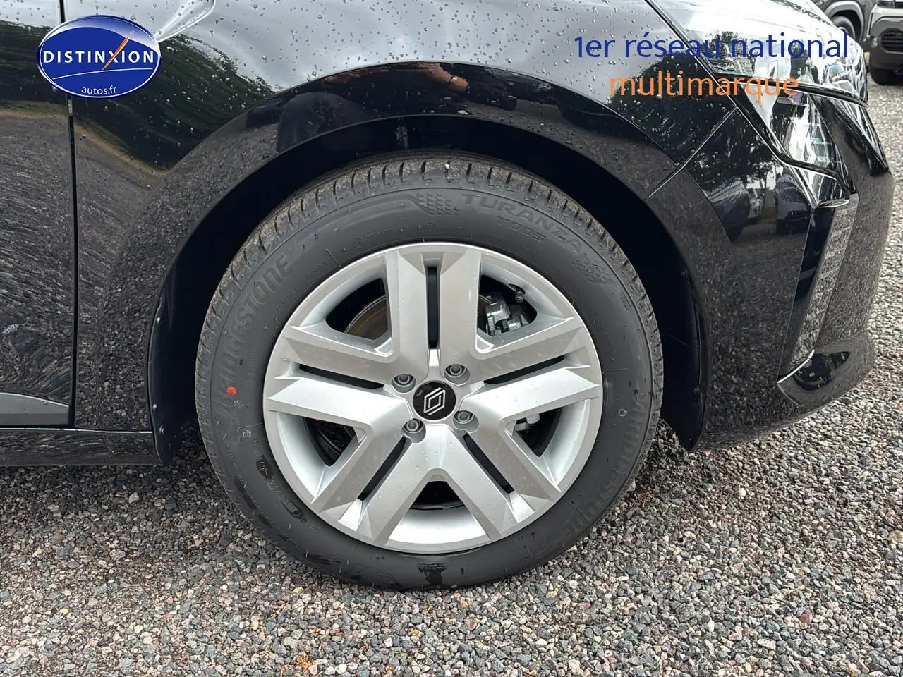 Gros plan sur la roue avant gauche de la Renault Clio V noire avec jante alliage et logo central distinctif.