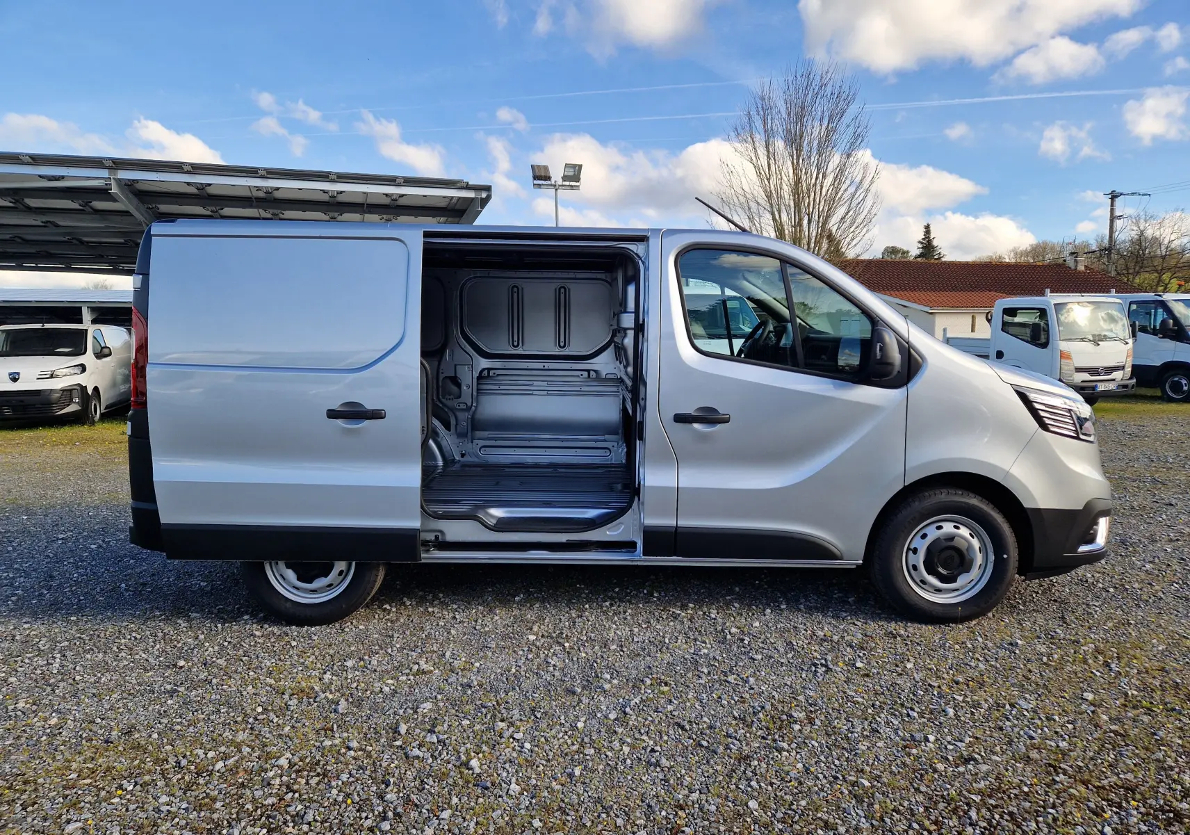 Renault Trafic Fourgon gris Highland vu de profil droit avec porte latérale coulissante ouverte montrant l’espace de chargement.