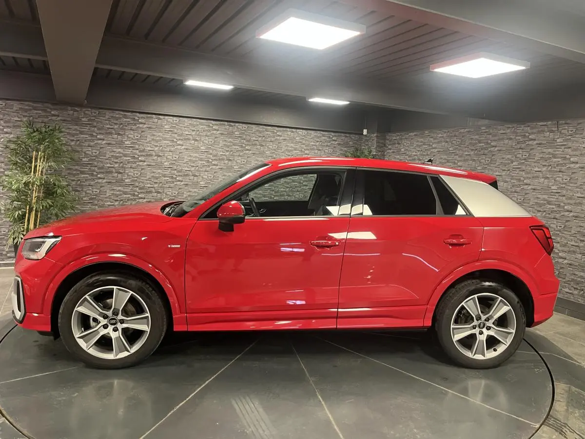 Audi Q2 S line rouge vue de profil côté gauche, toit et montant arrière blancs contrastants, jantes sport 5 branches.