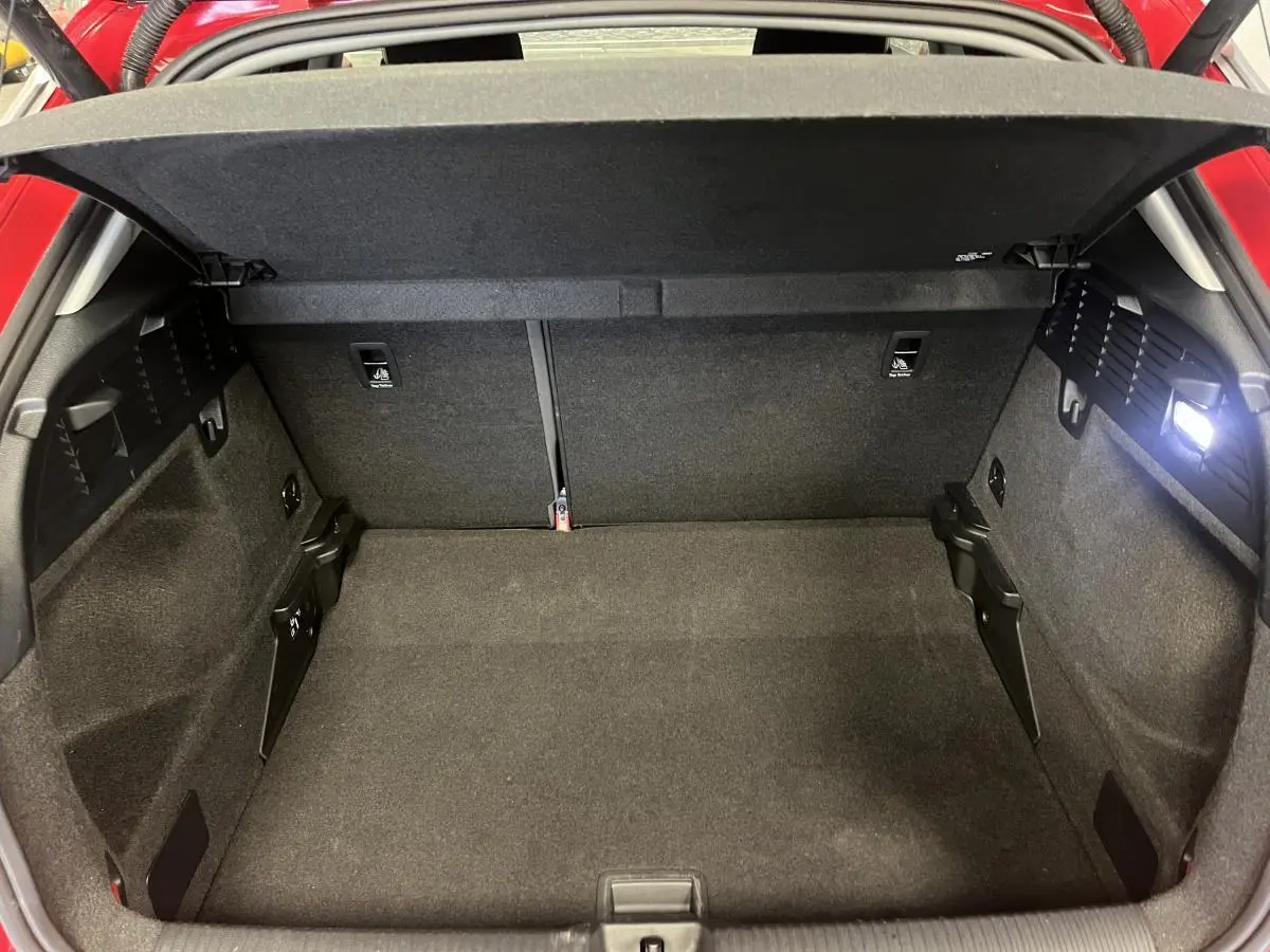 Vue intérieure du coffre ouvert de l'Audi Q2 rouge 2024, montrant un espace de rangement propre et bien éclairé.