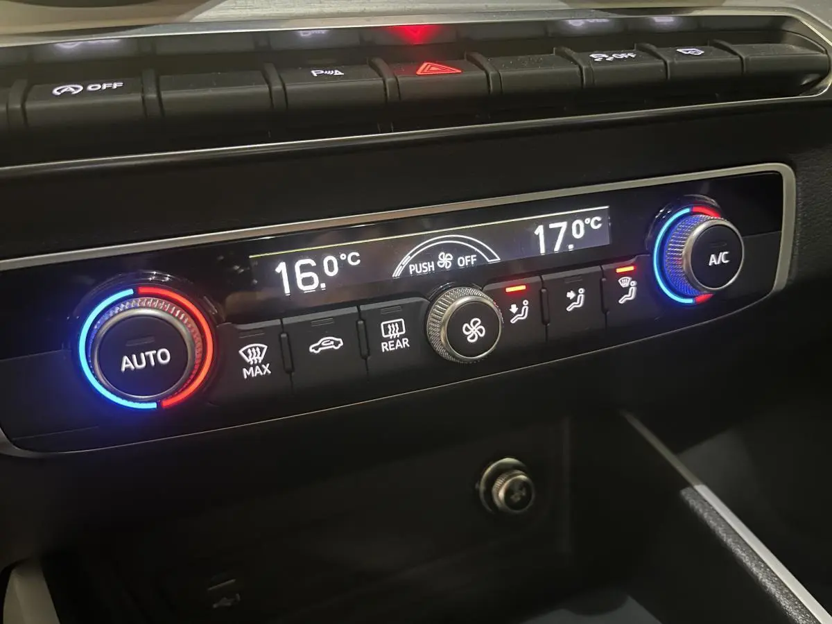 Panneau de commande de climatisation automatique de l'Audi Q2 2024 avec réglages numériques et boutons rétroéclairés.