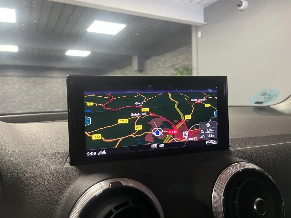 Vue intérieure du tableau de bord de l'Audi Q2 2024 avec écran de navigation affichant une carte routière.