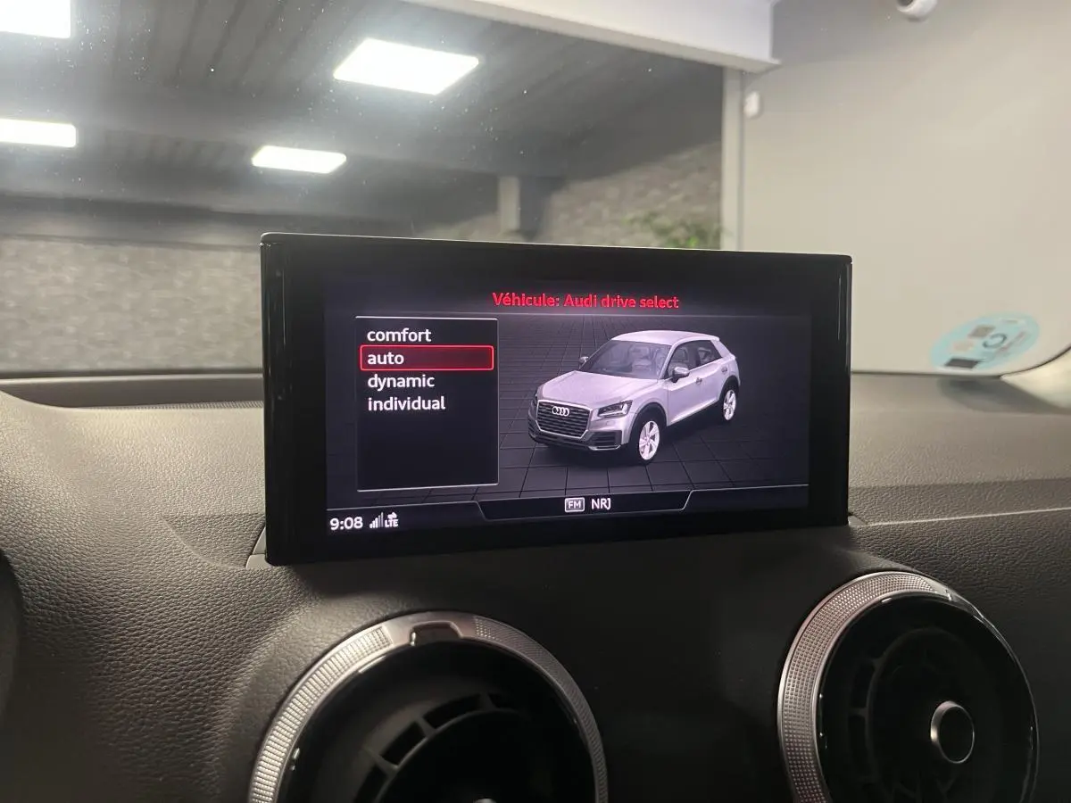 Écran intérieur affichant le mode Audi Drive Select avec une image 3/4 avant d'un Audi Q2 gris clair.