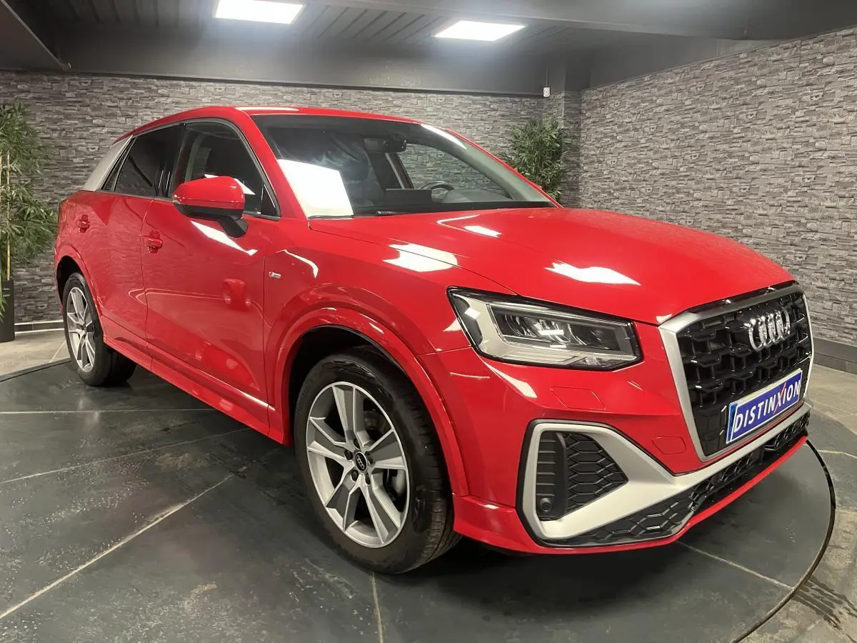 Audi Q2 S line rouge vue 3/4 avant droit, avec jantes 5 branches offroad et toit contrasté blanc.