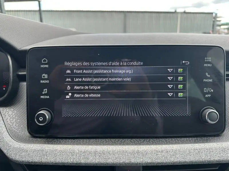 Écran tactile central du Skoda Scala gris graphite montrant les réglages d’aides à la conduite.