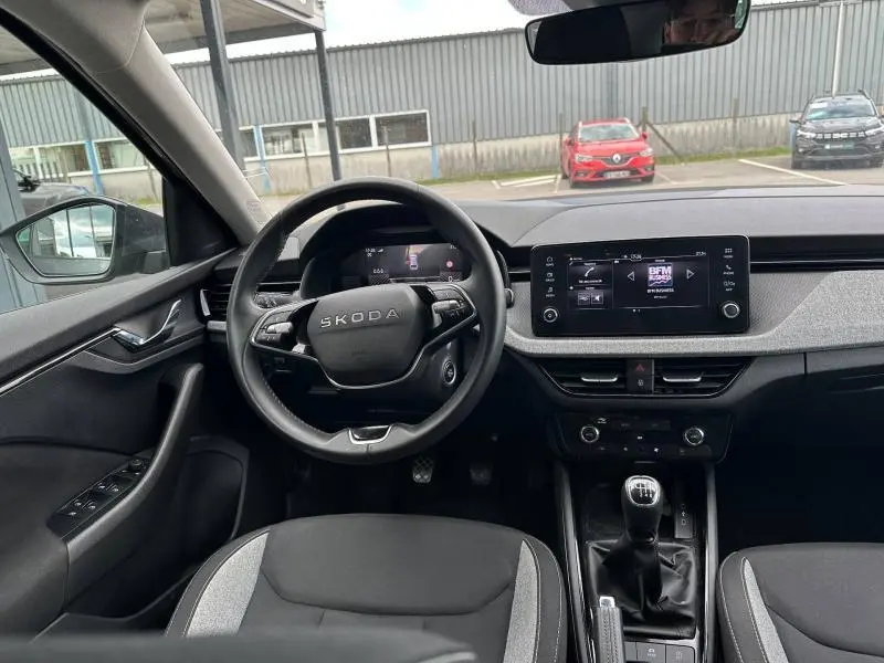 Vue intérieure avant du Skoda Scala gris graphite, volant cuir multifonction et écran tactile central visible.