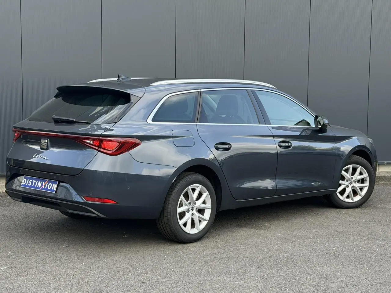 SEAT Leon ST gris magnétique vue 3/4 arrière droit, jantes alliage 16 pouces et vitres arrière surteintées.