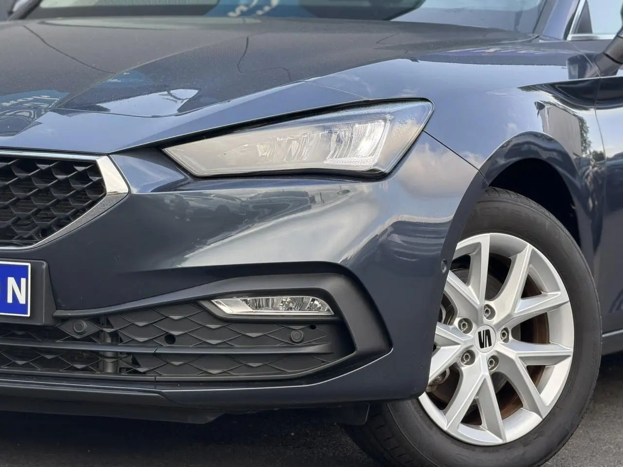 Gros plan sur l'avant droit gris magnétique du SEAT LEON ST 2025, mettant en valeur le phare LED et la jante alliage 16 pouces.