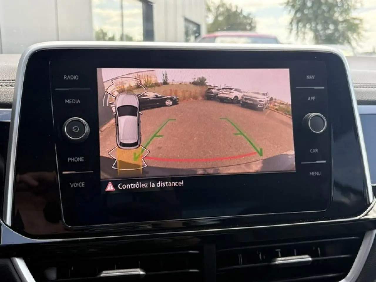 Écran tactile intérieur montrant la caméra de recul avec alertes de distance du Volkswagen T-Roc noir intense.
