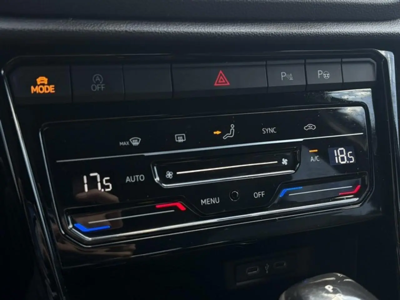 Gros plan sur la console centrale noire du Volkswagen T-Roc 2025, affichant la climatisation automatique bi-zone et commandes tactiles.